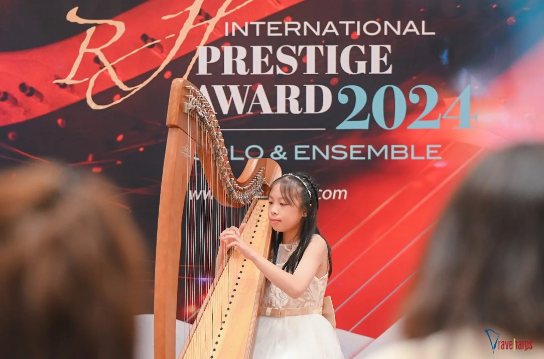 Young girl performing a harp recital on stage at an international music award event