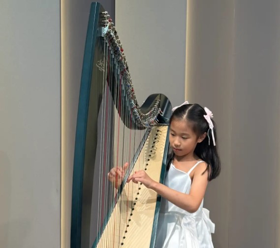Young girl focused on playing the harp, demonstrating effective harp practice with proper hand positioning and technique