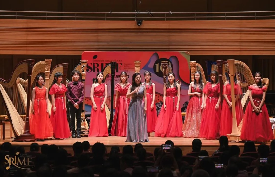 Harp students of Katryna on stage after a recital, posing with their instructor during a harp performance showcase.